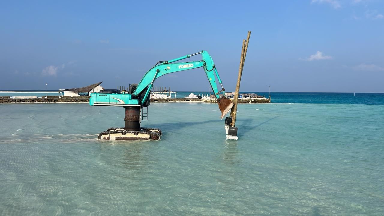 Long-reach excavator working from a pontoon in a Maldivian lagoon