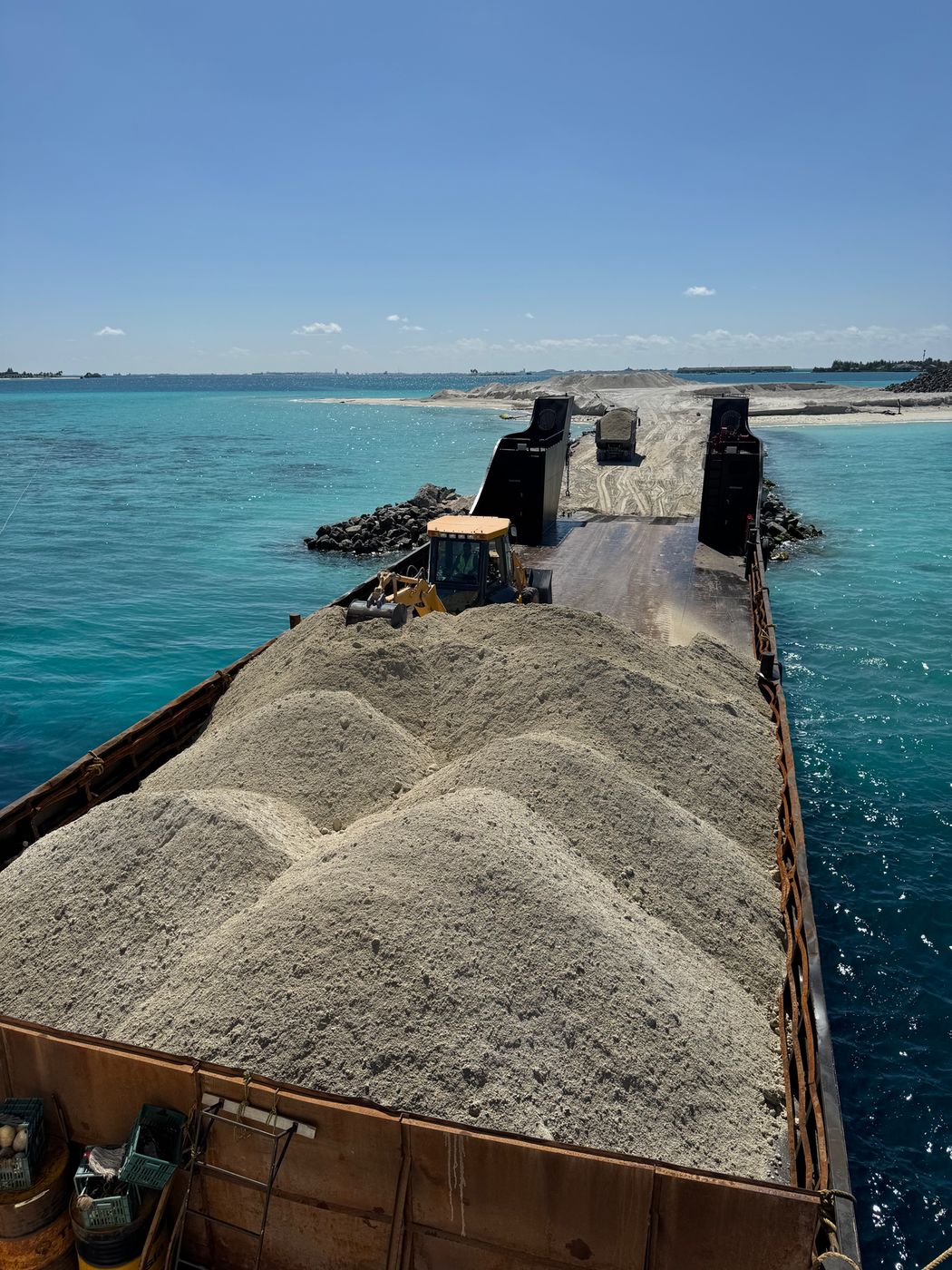 Landing craft loaded with coral sand under way between atolls