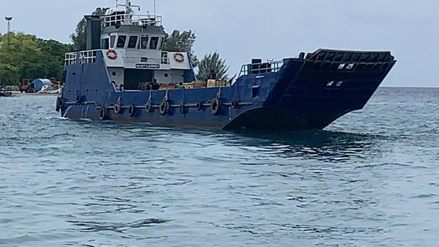 Landing craft with bow ramp lowered in shallow water